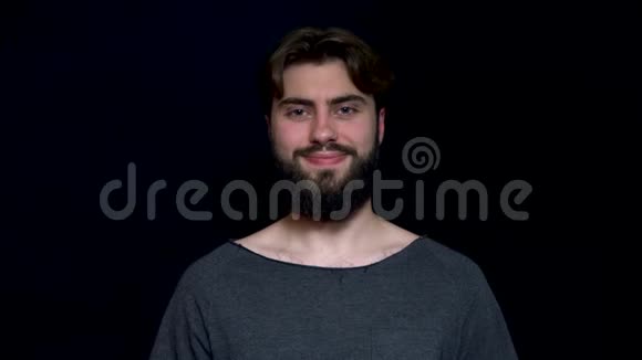 特写照片一个快乐的微笑胡须男子孤立在一个黑色的背景穿着灰色T恤的帅哥视频的预览图