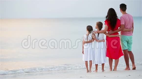 海滩上幸福美丽的家庭日落时父母和孩子的后景视频的预览图