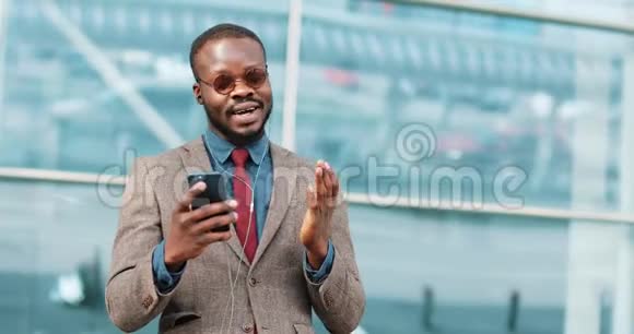 美国黑人年轻人使用智能手机视频聊天技术说话的画像就在办公中心旁边视频的预览图