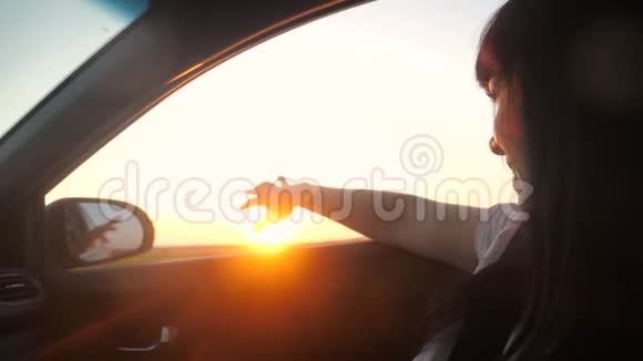 路旅游出行理念女孩挥手在窗户阳光下风在汽车慢动作视频黑发女郎视频的预览图