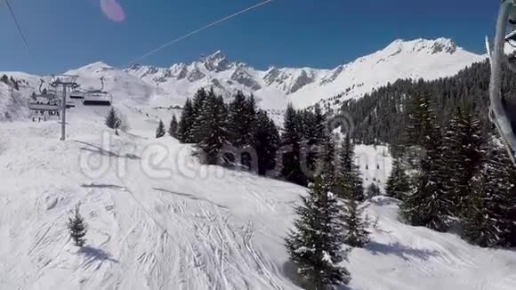 阳光明媚的冬季滑雪场椅式升降机升到山顶视频的预览图