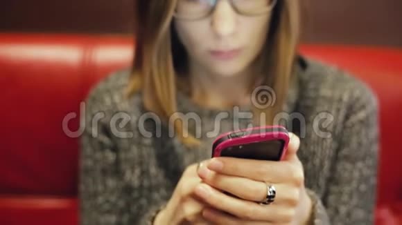 漂亮的眼镜女人在智能手机上使用应用程序与她的男朋友聊天视频的预览图