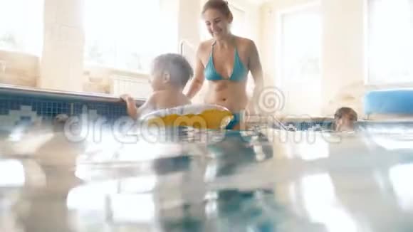 4k小童童在室内游泳池与母亲在充气圈游泳视频视频的预览图