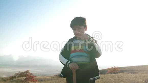 一个在山景背景上拿着木剑的男孩视频的预览图