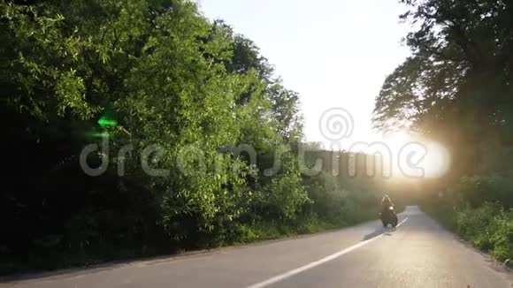 年轻的白人女孩骑摩托车在森林里坐在摄像机上日落或日出正视图有声视频的预览图