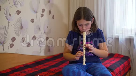 坐在床上练习长笛的女孩视频的预览图