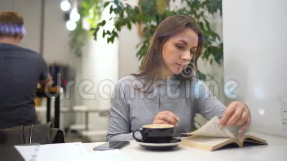 美丽的女人花时间在咖啡馆里看书和喝咖啡视频的预览图