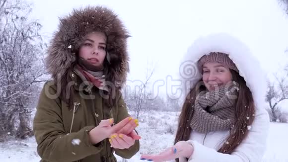 寒假美丽的女孩在开放的地方捕捉飞舞的雪花视频的预览图