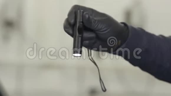在修理店里用黑色手套用窄光束举着黑色手电筒为男性的手合上行动男子手持视频的预览图