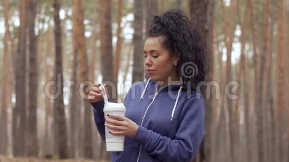 年轻漂亮的女人在森林里晨练时喝水视频的预览图