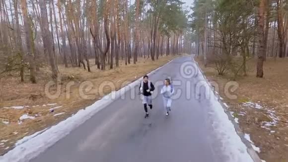 美丽的黑发女人和帅哥早上在森林里慢跑视频的预览图