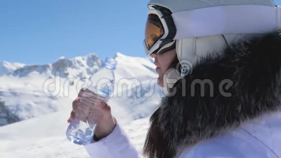 女滑雪者从山上的塑料瓶里喝干净的水视频的预览图