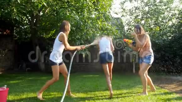 4k视频快乐的年轻家庭在炎热的晴天在花园里打水仗视频的预览图