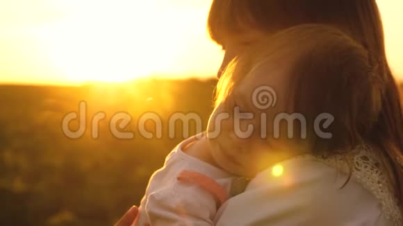小女孩正睡在年轻妈妈的怀里在金色的夕阳下慢动作视频的预览图