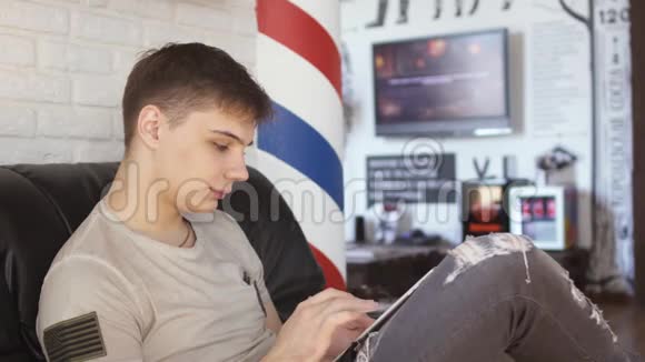 帅哥用平板电脑在理发店等轮到他视频的预览图