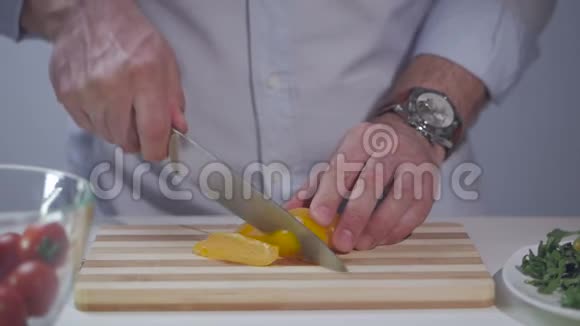 一个人用一把刀在一块分割的木板上切一根黄色的胡椒视频的预览图