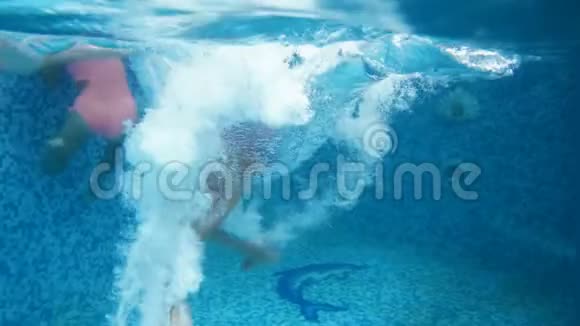 水下4k镜头两名少女在游泳池里跳跃和跳水视频的预览图