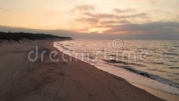 空中观看无人机镜头低飞行在一个废弃的海滩上日落带着滚滚海浪和夕阳的沙岸视频的预览图