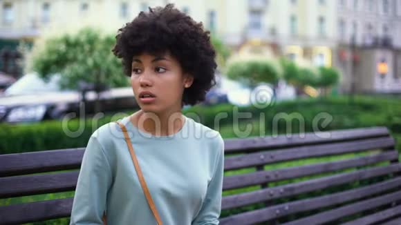 担心年轻女人在长凳上等男朋友在城市里浪漫约会爱视频的预览图