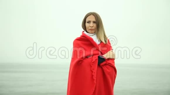 孤独悲伤的女孩穿着红毯在海边视频的预览图