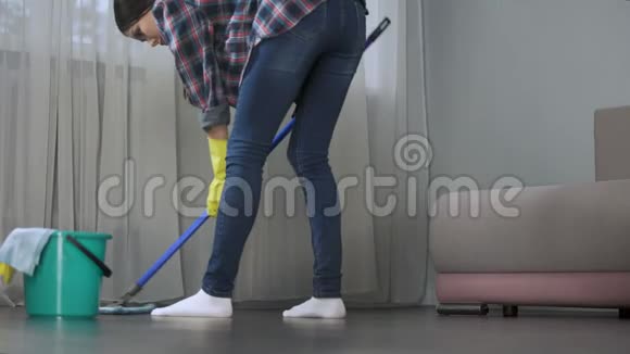 家庭主妇用拖把弹簧清洁在她的公寓里仔细地洗地板视频的预览图