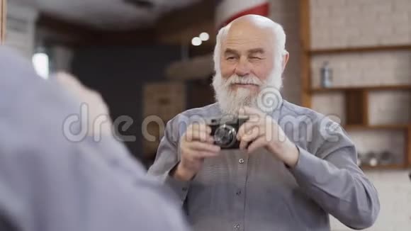 英俊的成熟男人用镜子里的旧相机自拍视频的预览图