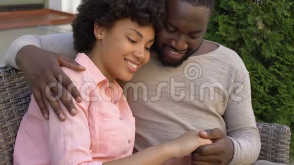 快乐的非洲夫妇在长凳上拥抱在城市咖啡馆里户外约会亲密无间视频的预览图