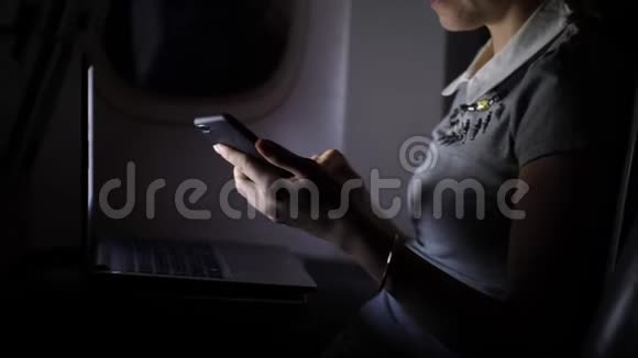 年轻女子晚上在飞机上用智能手机发短信视频的预览图