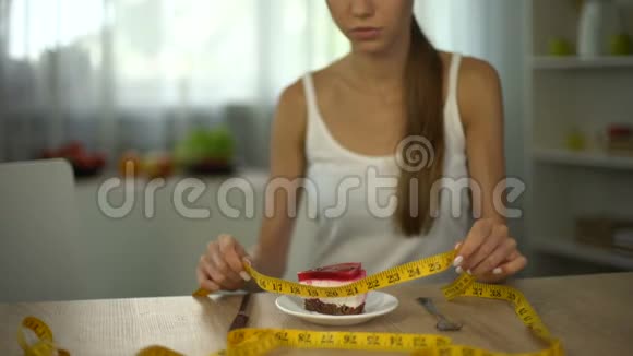 体重不足的女孩用胶带测量蛋糕害怕体重增加视频的预览图
