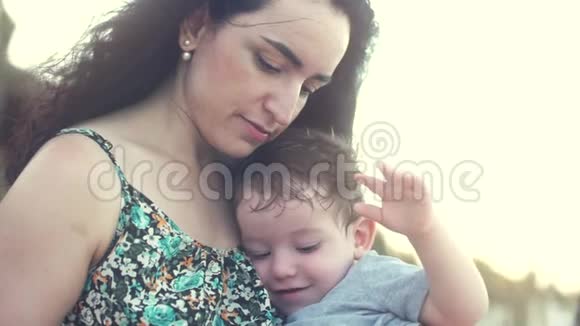 年轻的家庭母亲抱着儿子快乐的儿子抚摸着妈妈的手微笑视频的预览图