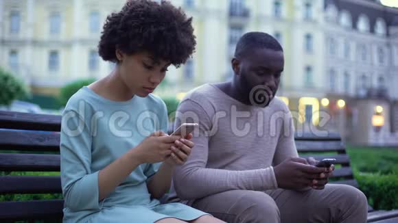 女朋友和男朋友在智能手机上聊天坐在长凳上不理睬视频的预览图