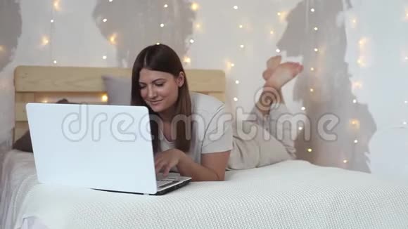 一个漂亮的女孩躺在床上喜欢笔记本电脑高清高清视频的预览图