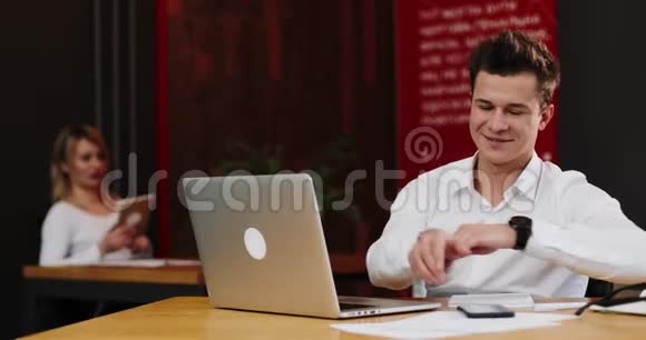 微笑着年轻的商人手提电脑和文件打电话给办公室的智能手机商业人视频的预览图