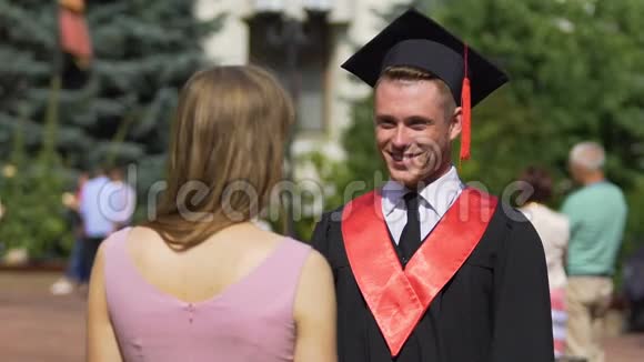 年轻女子祝贺和拥抱她的毕业男友快乐的时刻视频的预览图