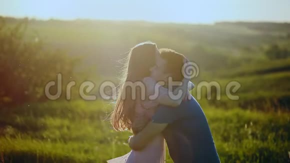 一对年轻漂亮的夫妇拥抱和亲吻自然日落时的田野视频的预览图