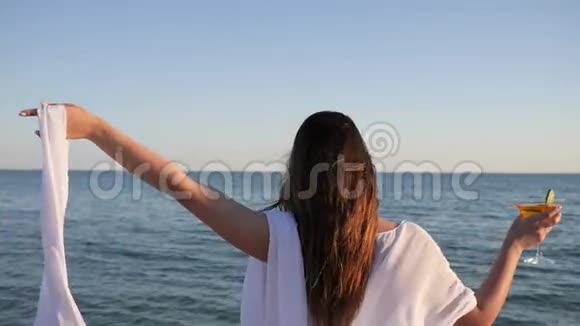 穿泳装的女孩在岸上女人在背景水上挥舞白布在海洋附近度假女性饮酒视频的预览图