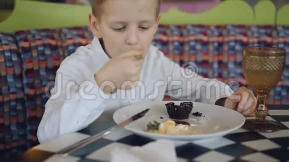 英俊的微笑男孩在咖啡馆里喝着美味的甜点4K视频的预览图