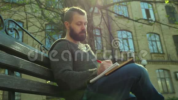 那个留胡子的人正坐在街上写一本书视频的预览图