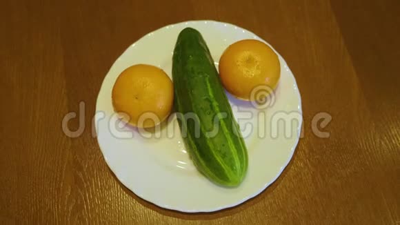 以黄瓜和盘子里的两个橘子制成的表情符号的静物视频的预览图