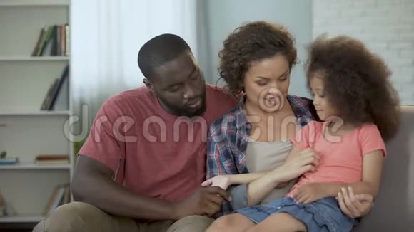 妈妈逗她的小女儿开心一家人坐在沙发上视频的预览图