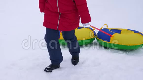 女孩抱着雪碟爬上雪山新鲜空气中的冬季游戏圣诞节视频的预览图