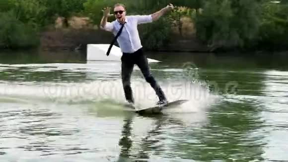 穿着西装戴着领带戴着太阳镜的极端快乐的商人在湖上的尾板上玩耍视频的预览图