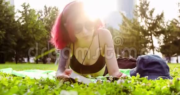 女孩在公园草地上放松和阅读一本书视频的预览图