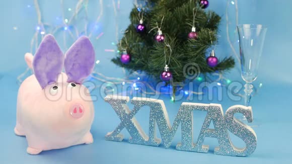 蓝色背景上的粉红色圣诞猪背景上有一棵圣诞树和圣诞铭文一个人倒着视频的预览图