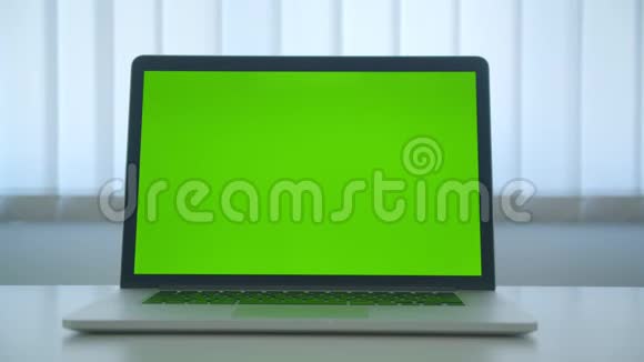 笔记本电脑的特写镜头带有绿色的彩色钥匙屏幕广告放在办公室室内的桌子上视频的预览图