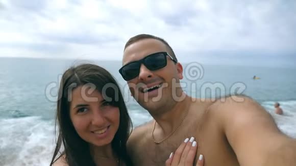 年轻的幸福夫妇在海边拍自我肖像微笑的一对在海边自拍性格开朗的人视频的预览图
