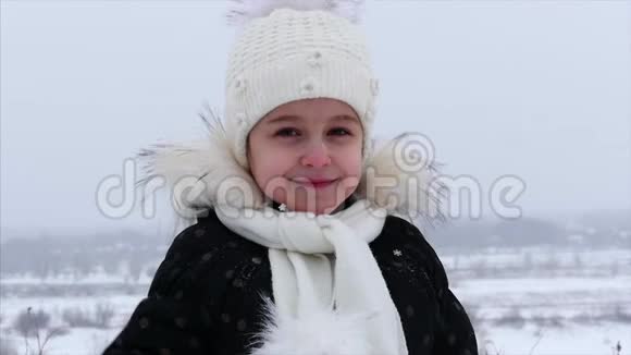 一个5岁的小女孩在冬天街上下雪她看着相机挥舞着手视频的预览图