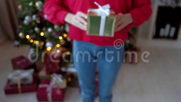 特写穿红色运动衫和蓝色牛仔裤的女孩送圣诞礼盒视频的预览图