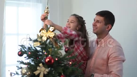 可爱的女孩把装饰星放在圣诞树顶上视频的预览图