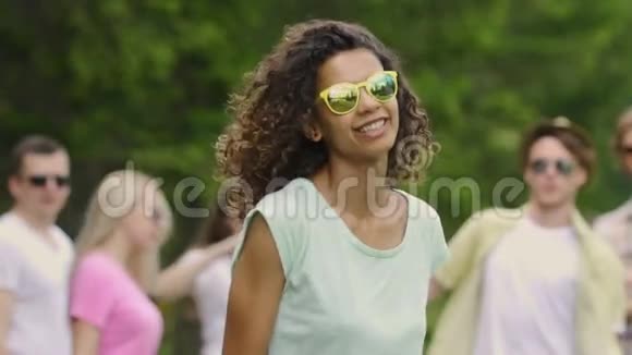 年轻漂亮的女人卷发在野餐时和朋友跳舞夏天视频的预览图